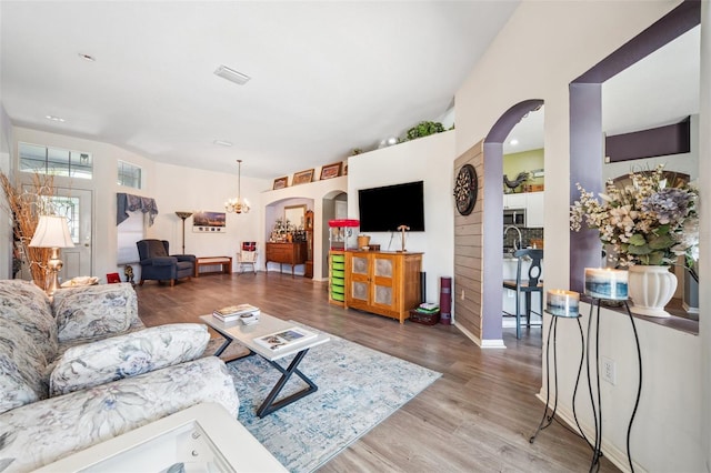 19750 Ellendale Dr, Land O Lakes, FL 34638 - living area featuring arched walkways, light wood-style floors, and a chandelier