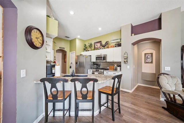 19750 Ellendale Dr, Land O Lakes, FL 34638 - kitchen featuring appliances with stainless steel finishes, arched walkways, a peninsula, a kitchen bar, and backsplash