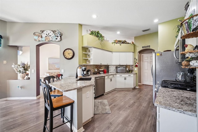 19750 Ellendale Dr, Land O Lakes, FL 34638 - kitchen with arched walkways, appliances with stainless steel finishes, open shelves, a peninsula, and decorative backsplash