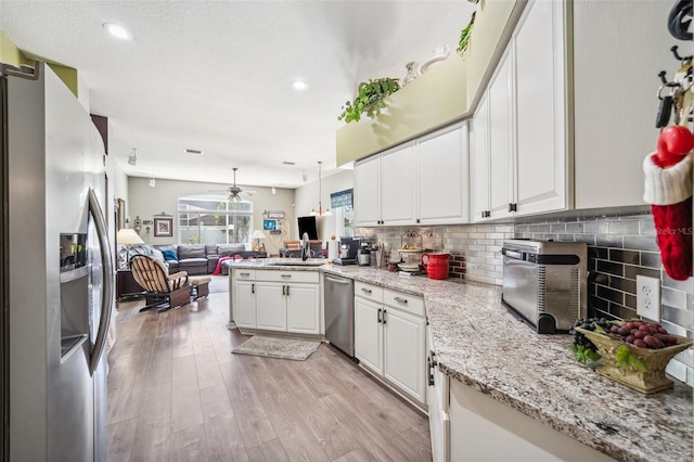 19750 Ellendale Dr, Land O Lakes, FL 34638 - kitchen with appliances with stainless steel finishes, open floor plan, white cabinets, backsplash, and a peninsula
