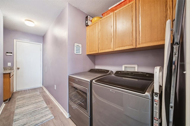 19750 Ellendale Dr, Land O Lakes, FL 34638 - laundry room featuring cabinet space, washing machine and dryer, light wood-style flooring, and a textured ceiling