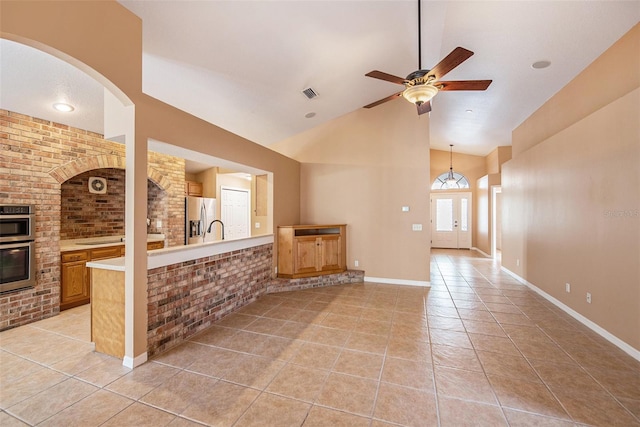 6711 Thackston Dr, Riverview, FL 33578 - unfurnished living room with brick wall, light tile patterned floors, ceiling fan, high vaulted ceiling, and baseboards