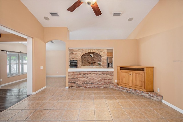 6711 Thackston Dr, Riverview, FL 33578 - unfurnished living room featuring vaulted ceiling, a ceiling fan, tile patterned flooring, arched walkways, and baseboards