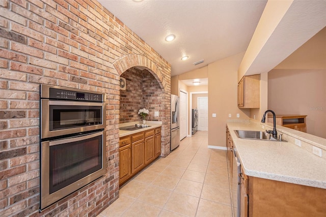 6711 Thackston Dr, Riverview, FL 33578 - kitchen featuring stainless steel appliances, a sink, light tile patterned floors, brick wall, and a peninsula
