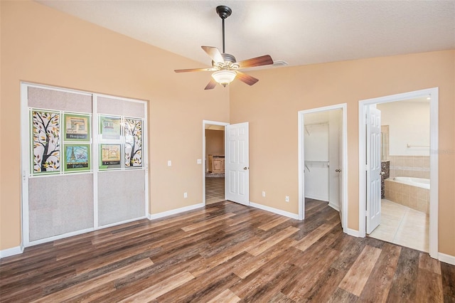 6711 Thackston Dr, Riverview, FL 33578 - unfurnished bedroom with wood finished floors, ensuite bathroom, baseboards, a walk in closet, and lofted ceiling