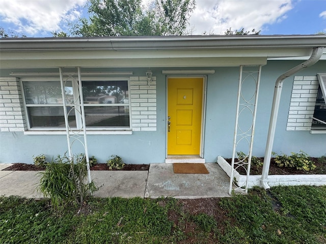 property entrance with stucco siding and brick siding