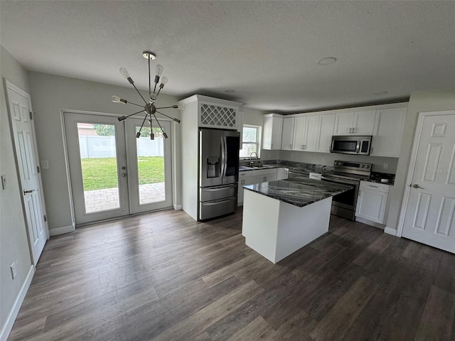 kitchen with a sink, dark wood-style flooring, appliances with stainless steel finishes, a chandelier, and white cabinetry