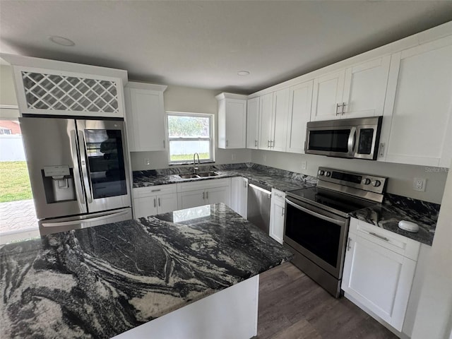 kitchen with a sink, dark wood finished floors, white cabinetry, dark stone counters, and stainless steel appliances