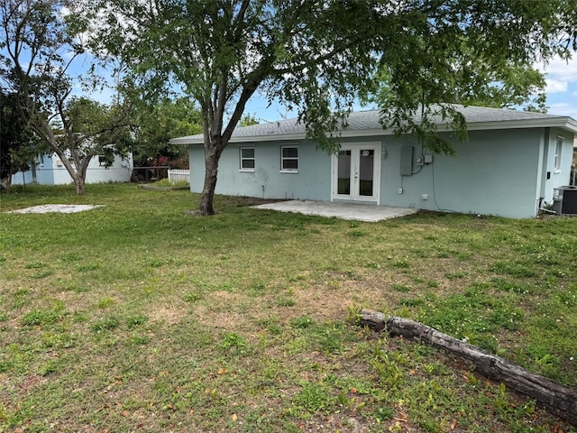rear view of property featuring a patio area, a yard, fence, stucco siding, and french doors