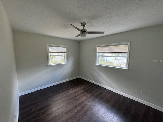 unfurnished room featuring baseboards, plenty of natural light, ceiling fan, and dark wood finished floors