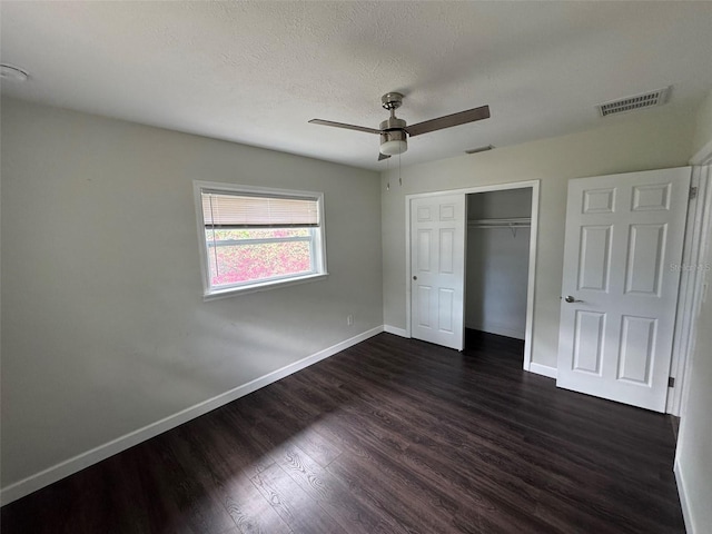 unfurnished bedroom with visible vents, baseboards, a closet, a textured ceiling, and dark wood-style floors