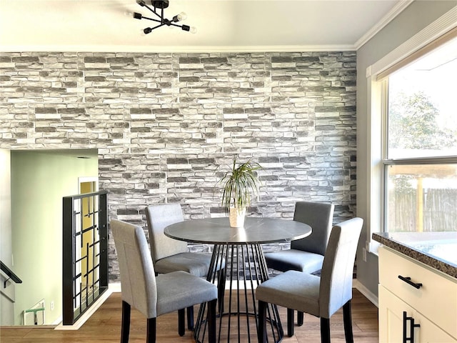 dining space featuring wood finished floors and crown molding