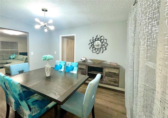 dining room featuring an inviting chandelier, a textured ceiling, and wood finished floors