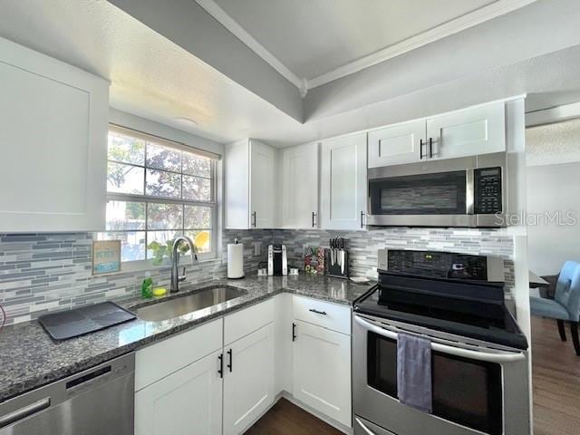 kitchen with stone counters, stainless steel appliances, ornamental molding, and a sink