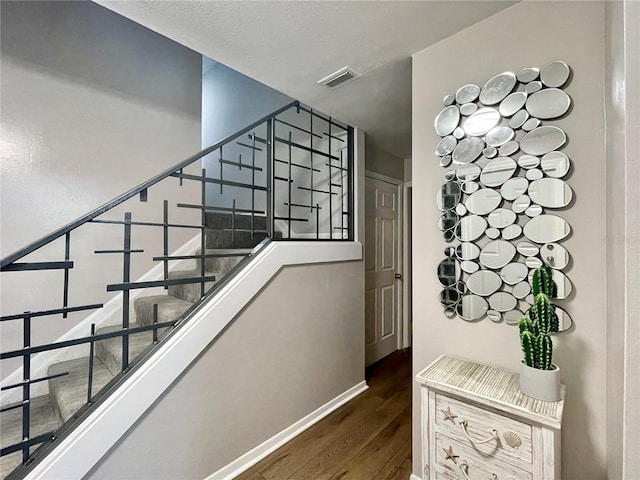 stairs featuring baseboards, visible vents, and wood finished floors