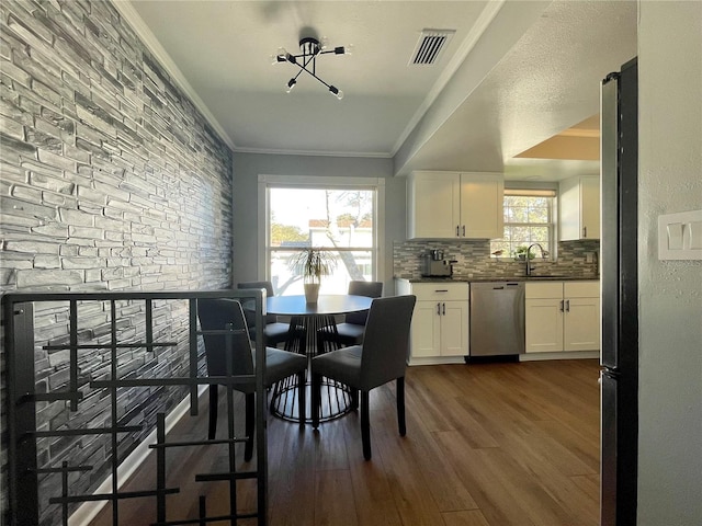 dining area with dark wood-style flooring, visible vents, and crown molding