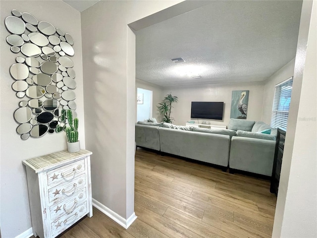 living room featuring a textured ceiling, visible vents, wood finished floors, and baseboards