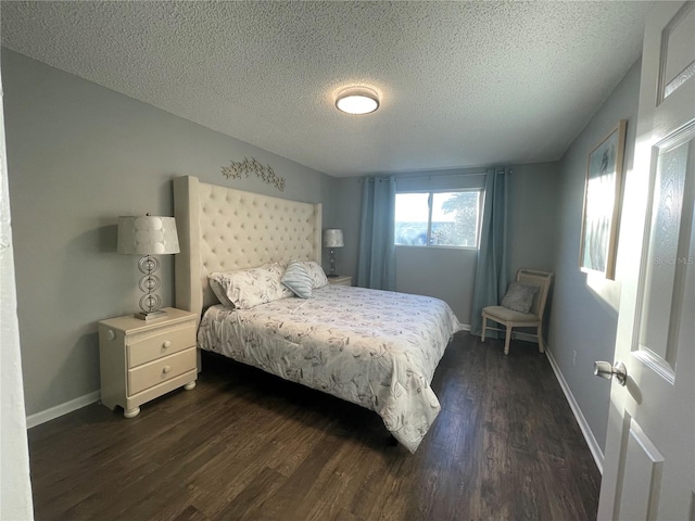 bedroom with dark wood finished floors, baseboards, and a textured ceiling
