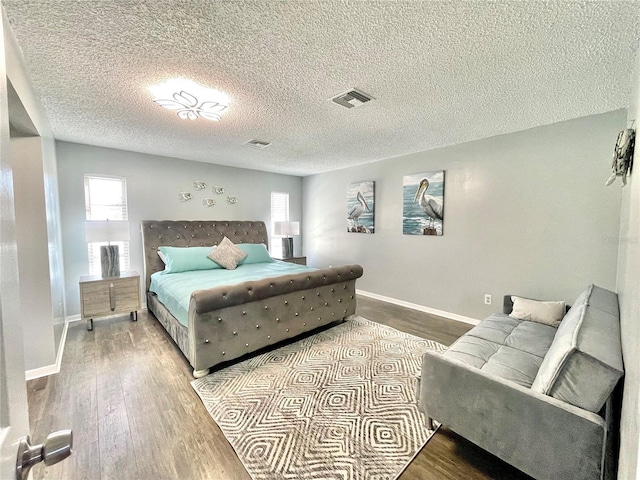 bedroom featuring visible vents, wood finished floors, multiple windows, and baseboards