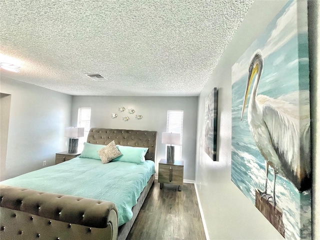 bedroom featuring a textured ceiling, visible vents, wood finished floors, and baseboards