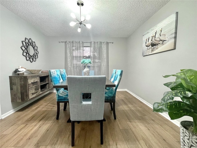 dining area with a textured ceiling, wood finished floors, and a chandelier