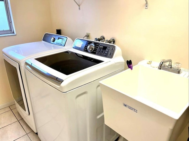 laundry area with light tile patterned floors, washer and dryer, laundry area, and a sink