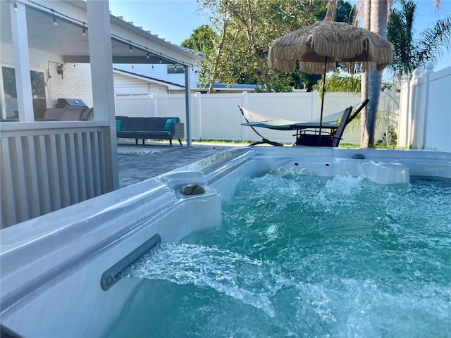 view of pool with fence, a wooden deck, a hot tub, and an outdoor hangout area