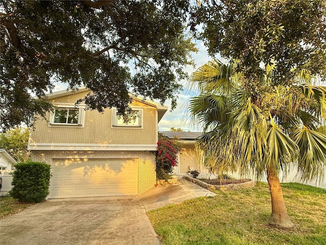 view of front of property with a front yard, driveway, a garage, and brick siding