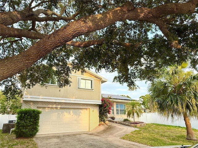 view of front of property with a front yard, a garage, driveway, brick siding, and fence