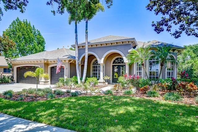 3212 Sunset Lakes Blvd, Land O Lakes, FL 34638 - mediterranean / spanish-style house featuring a garage, stucco siding, a front yard, concrete driveway, and french doors