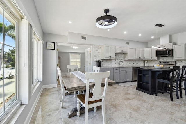 kitchen with visible vents, a kitchen island, a sink, stainless steel appliances, and decorative backsplash