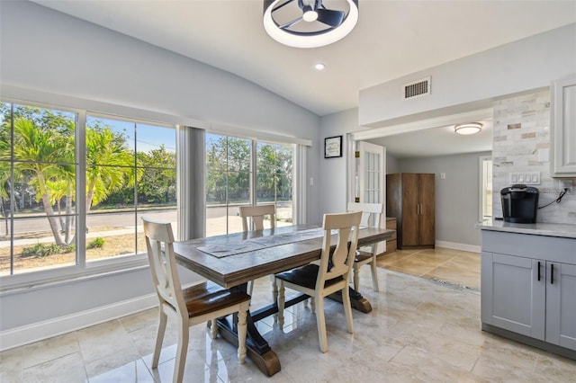 dining room with visible vents, baseboards, plenty of natural light, and vaulted ceiling