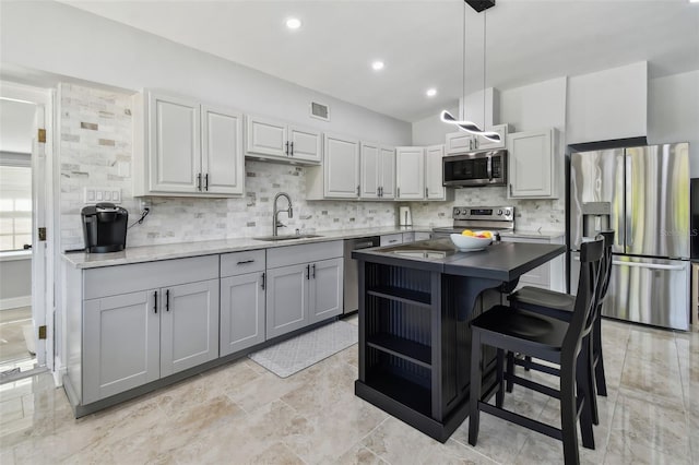kitchen featuring tasteful backsplash, visible vents, stainless steel appliances, pendant lighting, and a sink