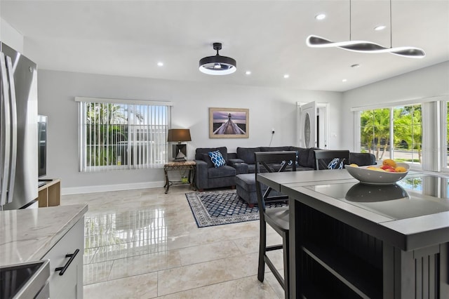 kitchen with range, freestanding refrigerator, recessed lighting, decorative light fixtures, and baseboards
