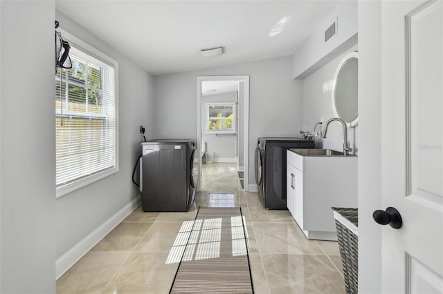 washroom with a healthy amount of sunlight, separate washer and dryer, baseboards, and cabinet space