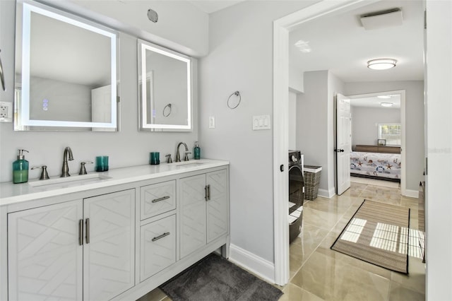 bathroom with a sink, ensuite bathroom, baseboards, and double vanity