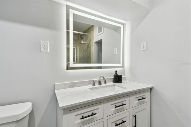 bathroom with a shower stall, vanity, visible vents, and toilet
