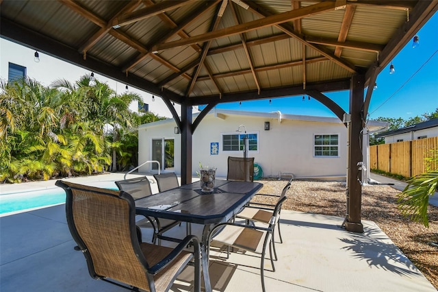 view of patio with outdoor dining space, a fenced in pool, fence, and a gazebo
