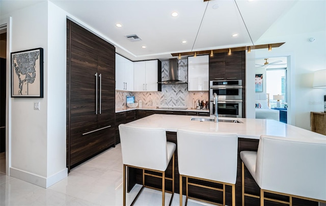 301 1st St S Unit 3004, Saint Petersburg, FL 33701 - kitchen featuring wall chimney range hood, tasteful backsplash, a sink, light countertops, and a kitchen bar