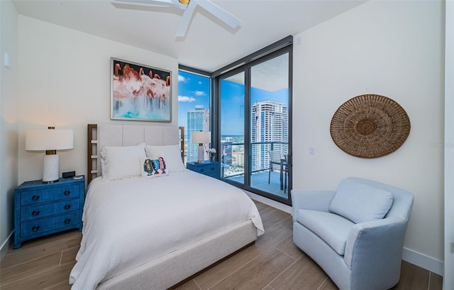 301 1st St S Unit 3004, Saint Petersburg, FL 33701 - bedroom featuring access to exterior, baseboards, wood finished floors, floor to ceiling windows, and a view of city