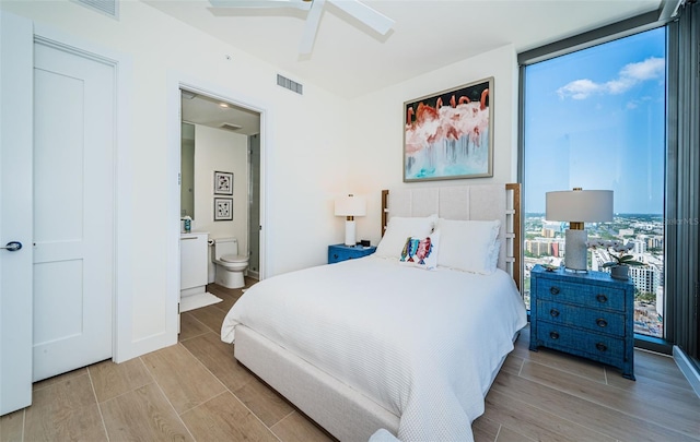 301 1st St S Unit 3004, Saint Petersburg, FL 33701 - bedroom with light wood finished floors, visible vents, ensuite bath, expansive windows, and ceiling fan