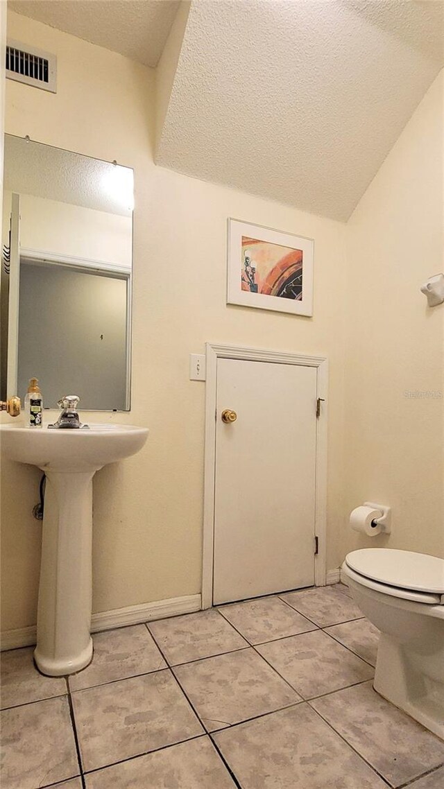 2213 Fluorshire Dr, Brandon, FL 33511 - bathroom with a textured ceiling, tile patterned flooring, lofted ceiling, toilet, and baseboards
