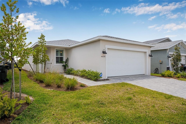 44239 Frontier Dr, Punta Gorda, FL 33982 - view of front of house featuring an attached garage, stucco siding, a front yard, and decorative driveway