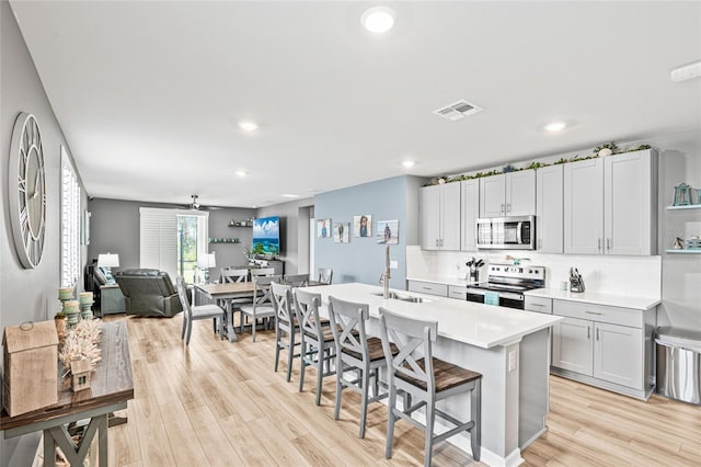 44239 Frontier Dr, Punta Gorda, FL 33982 - kitchen with light wood-type flooring, light countertops, a kitchen bar, appliances with stainless steel finishes, and a sink