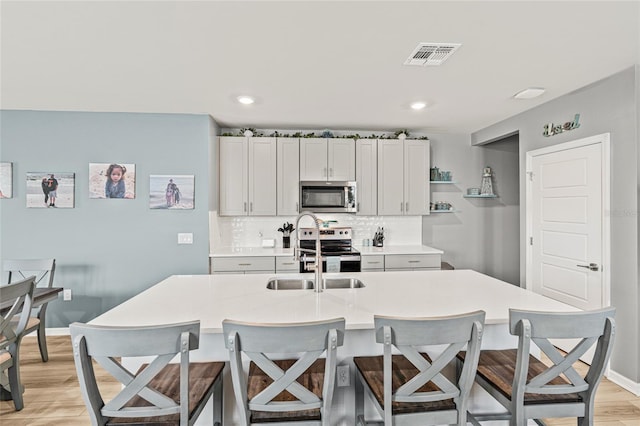 44239 Frontier Dr, Punta Gorda, FL 33982 - kitchen featuring visible vents, appliances with stainless steel finishes, a sink, a breakfast bar area, and backsplash