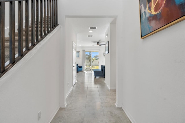 corridor with light tile patterned floors, baseboards, visible vents, and stairs