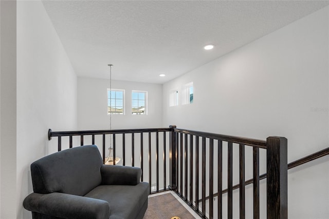 living area featuring an upstairs landing, recessed lighting, dark colored carpet, and a textured ceiling