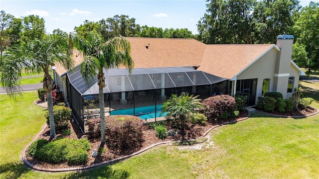 back of property with a chimney, an outdoor pool, a yard, stucco siding, and a lanai