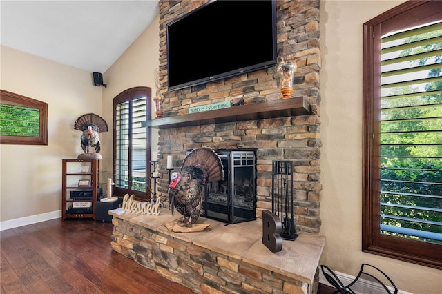 living room with lofted ceiling, baseboards, a stone fireplace, and wood finished floors