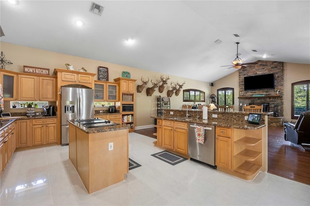 kitchen with ceiling fan, a center island with sink, stainless steel appliances, and a sink